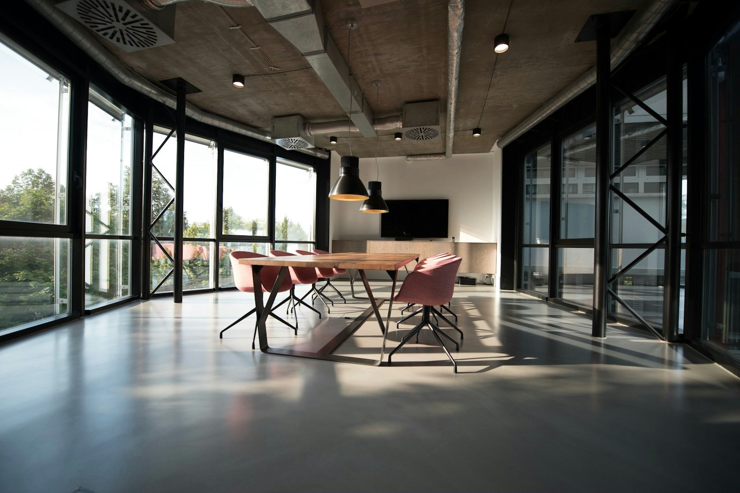 Sunlit office meeting room with a tidy table, chairs and floor-to-ceiling windows